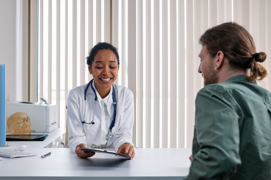 Médecin souriante échangeant avec un patient lors d’une consultation