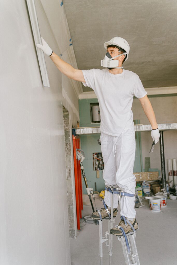 Plâtrier sur échasses finissant un mur de chantier
